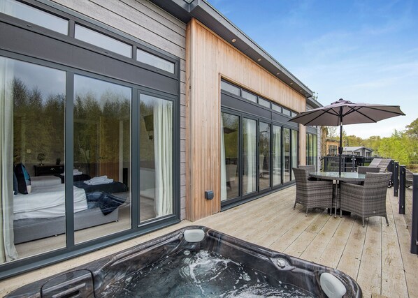 Un bâtiment moderne doté de grandes portes coulissantes en verre, d’un jacuzzi et de mobilier d’extérieur.