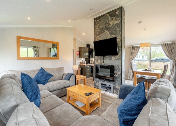 A modern living room with a sofa, coffee table, and a fireplace. - New in 2018. Modern and luxurious lodge with lakeside view. (Woodhall Spa)