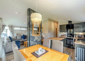 A modern living room with a sofa, a dining table, and a kitchen area with appliances.