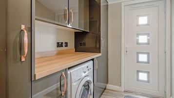 A compact kitchen with a washing machine, a microwave, and a built-in oven.