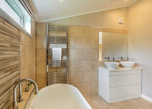 A modern bathroom with a freestanding bathtub, two vessel sinks, a large mirror, and a towel rack. - New in 2018. Modern and luxurious lodge with lakeside view. (Woodhall Spa)