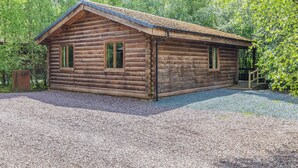 A log cabin with a gravel driveway and a wooden porch. - 2 bedroom accommodation in Freehay, Cheadle (Freehay, Cheadle)