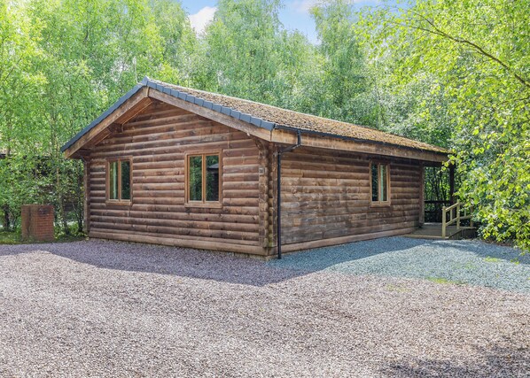 A log cabin with a gravel driveway and a wooden porch. - 1 bedroom accommodation in Freehay, Cheadle (Freehay, Cheadle)