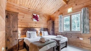 A wooden cabin room with two beds, a window with curtains, and a wall-mounted picture. - 2 bedroom accommodation in Freehay, Cheadle (Freehay, Cheadle)