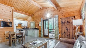 A wooden cabin interior with a dining area, kitchen, and a sofa. - 2 bedroom accommodation in Freehay, Cheadle (Freehay, Cheadle)