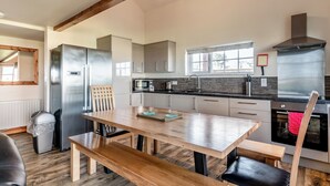 Una cocina moderna con electrodomésticos de acero inoxidable, vigas de madera y un ventanal grande.