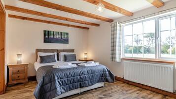 Une chambre à coucher avec un lit, des tables de chevet, une fenêtre et un radiateur.
