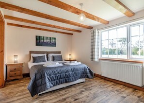 Une chambre à coucher avec un lit, des tables de chevet, une fenêtre et un radiateur.