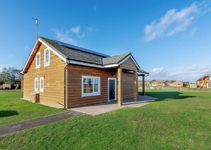 Une cabane en rondins avec une véranda, une porte et une fenêtre.