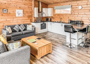 Un intérieur de chalet chaleureux comprenant un espace de vie, une kitchenette et un coin repas.
