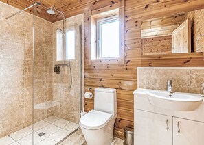 Une salle de bain avec une douche à parois de verre, des toilettes, un lavabo et un lambris en bois.