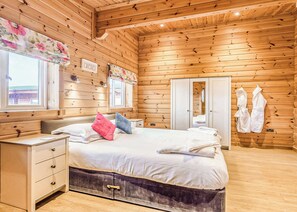 Ein Zimmer mit Holzwänden, einem Bett, einem Nachttisch und einem Kleiderschrank.