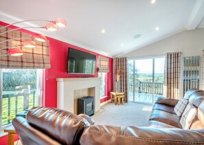 A living room with a fireplace, leather sofa, television, and a balcony with a view.