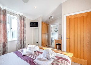 Une chambre à coucher avec un lit, des serviettes, un miroir, une armoire et un panneau sur lequel est écrit le mot « AMOUR ».
