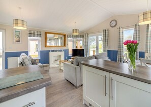 A modern kitchen with a built-in oven, a dining area with a sofa, and a living room with a television.