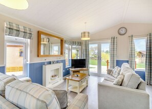 A living room with a fireplace, sofa, television, and a view of the outdoors. - 2 bedroom accommodation in Swinethorpe, Nr Lincoln (Swinethorpe, Nr Lincoln)