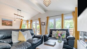 A modern living room with leather sofas, a wooden coffee table, and a chandelier. - Bakewell Deluxe Lodge Pet Friendly (Longnor, Nr. Buxton)