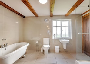 Ein Badezimmer mit Badewanne, Toilette, Waschbecken und einem Fenster.