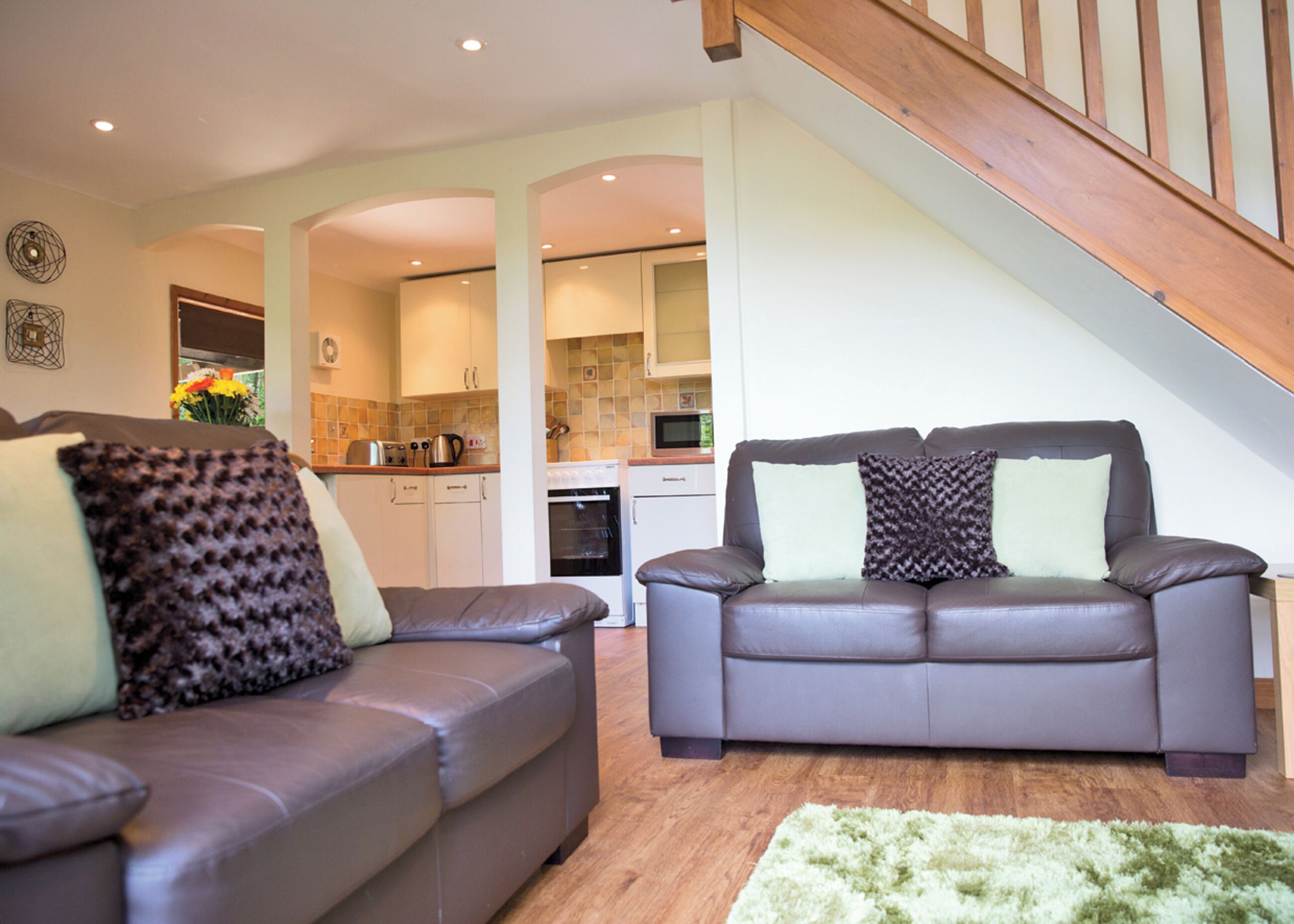A living room with two sofas, a staircase, and a kitchen in the background.