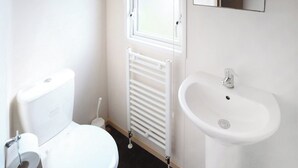 Un bagno piccolo e pulito con il water, un termosifone bianco e un lavandino.