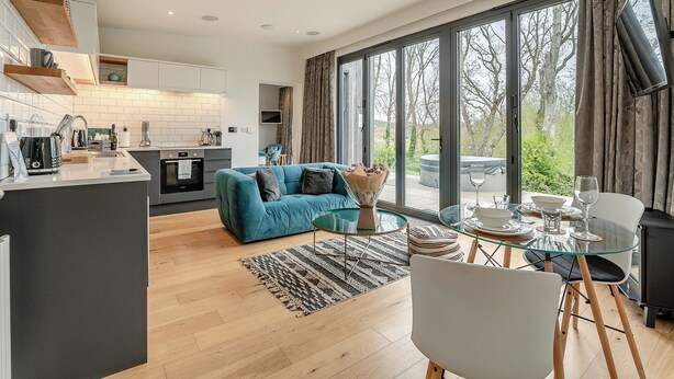 A modern living space with a kitchen, dining area, and large windows. - Woodland View Retreat (Pet) (Lewes)
