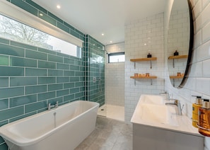 A modern bathroom with a bathtub, shower, and vanity.