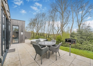 An outdoor patio with a round table and chairs, a hot tub, and a barbecue grill.
