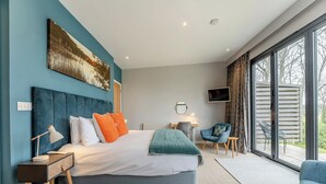 A modern bedroom with a large bed, a desk, a chair, and a TV. - Woodland View Retreat (Pet) (Lewes)