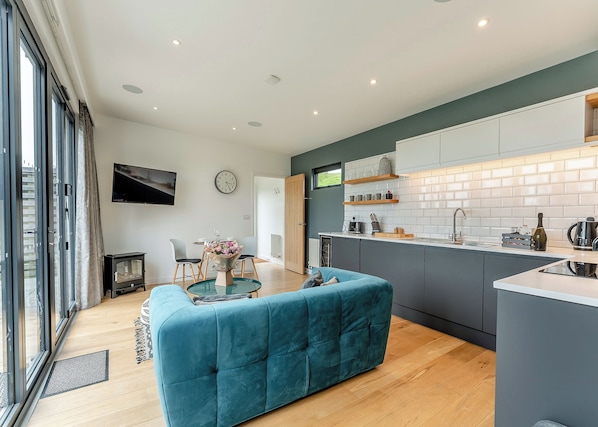 A modern kitchen with a central island, a dining area with a table and chairs, and a living space with a sofa.