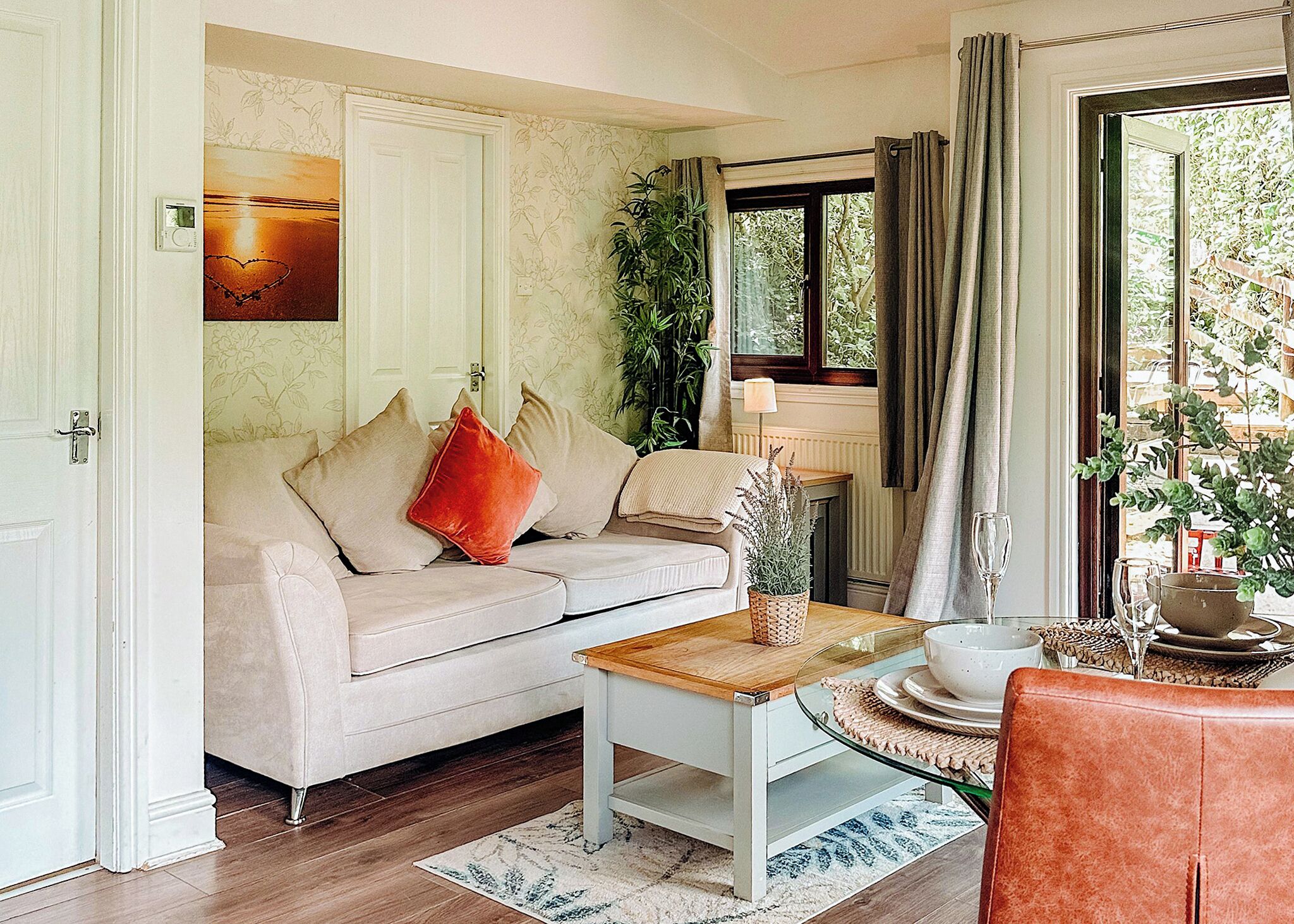 Un salon avec un canapé, une table basse, une fenêtre avec des rideaux, une plante et une cheminée.