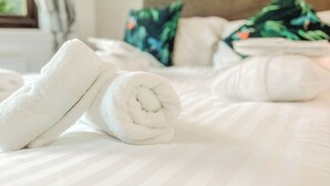 A neatly made bed with rolled white towels and a headboard with floral pillows. - Kingfisher Lakeside Lodge (Caerwys, Flintshire)