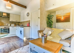A modern kitchen with appliances, a dining area with a table, and a living room with a sofa and a plant. - Kingfisher Lakeside Lodge (Caerwys, Flintshire)