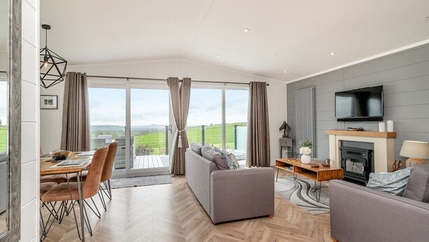 A spacious living room with a fireplace, a television, and a dining area with a view.