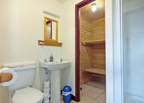 A bathroom with a toilet, sink, mirror, and wooden shower enclosure. - Cottage with one double and two twin. (St Clears)