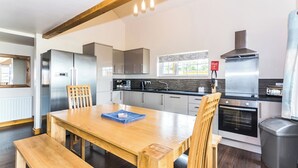 Una cocina moderna con electrodomésticos de acero inoxidable, una mesa de comedor de madera y un horno empotrado.