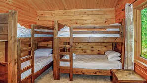 Une cabane aux murs en bois, avec des lits superposés et une petite table.