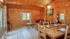 L'intérieur d'un chalet en bois, avec une table à manger, des chaises, un canapé et un tableau accroché au mur.