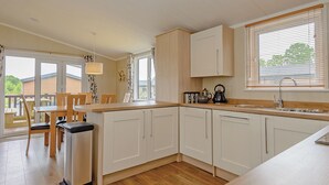 Una cocina moderna con armarios blancos, encimera de madera y una ventana con persianas.