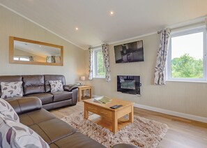 A living room with a sofa, a coffee table, a TV, and a window with curtains.