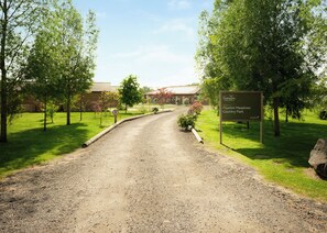 Ein Schotterweg führt zu einem Gebäude, an dem ein Schild an den Faxton Meadows Country Park willkommen heißt.