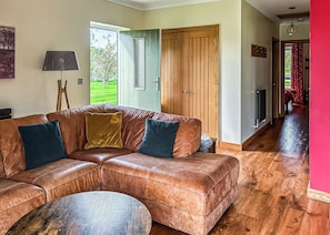 A living room with a brown leather sofa, a round coffee table, and a wooden door.