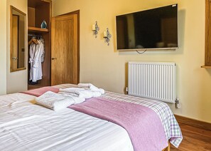 Ein Schlafzimmer mit Bett, Fernseher, Heizkörper und Kleiderschrank.