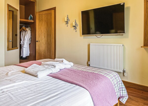 A bedroom with a bed, a television, a radiator, and a wardrobe. - 1 bedroom accommodation in Flaxton (Flaxton)