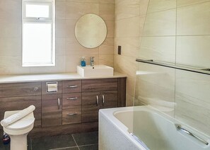 Un baño con bañera, lavamanos, espejo y ventana.