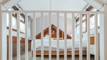 A bedroom with a sloped ceiling, a wooden headboard, and a white bedspread.