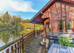 A wooden cabin with a dock extending into a lake, surrounded by trees.