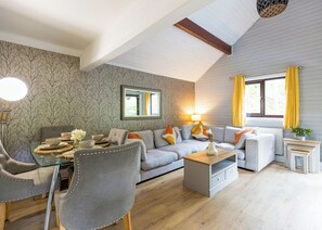 A living room with a sofa, chairs, a coffee table, and a dining table set with bowls and flowers.