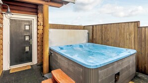 Un jacuzzi con cubierta de madera, un banco y una puerta con paneles de vidrio.