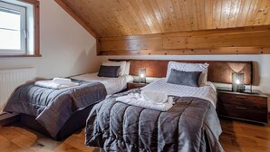 Un dormitorio con dos camas, vigas de madera en el techo, una ventana y lámparas de noche.