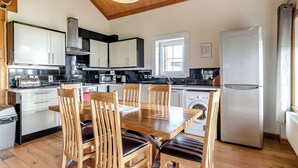 Una cocina moderna con armarios de madera, una mesa de comedor con sillas, una lavadora y un refrigerador.
